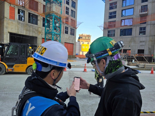 DL이앤씨 직원이 수도권의 한 아파트 건설현장에서 외국인 노동자에게 'AI 자동번역 시스템'을 안내하고 있다. [DL이앤씨 제공]